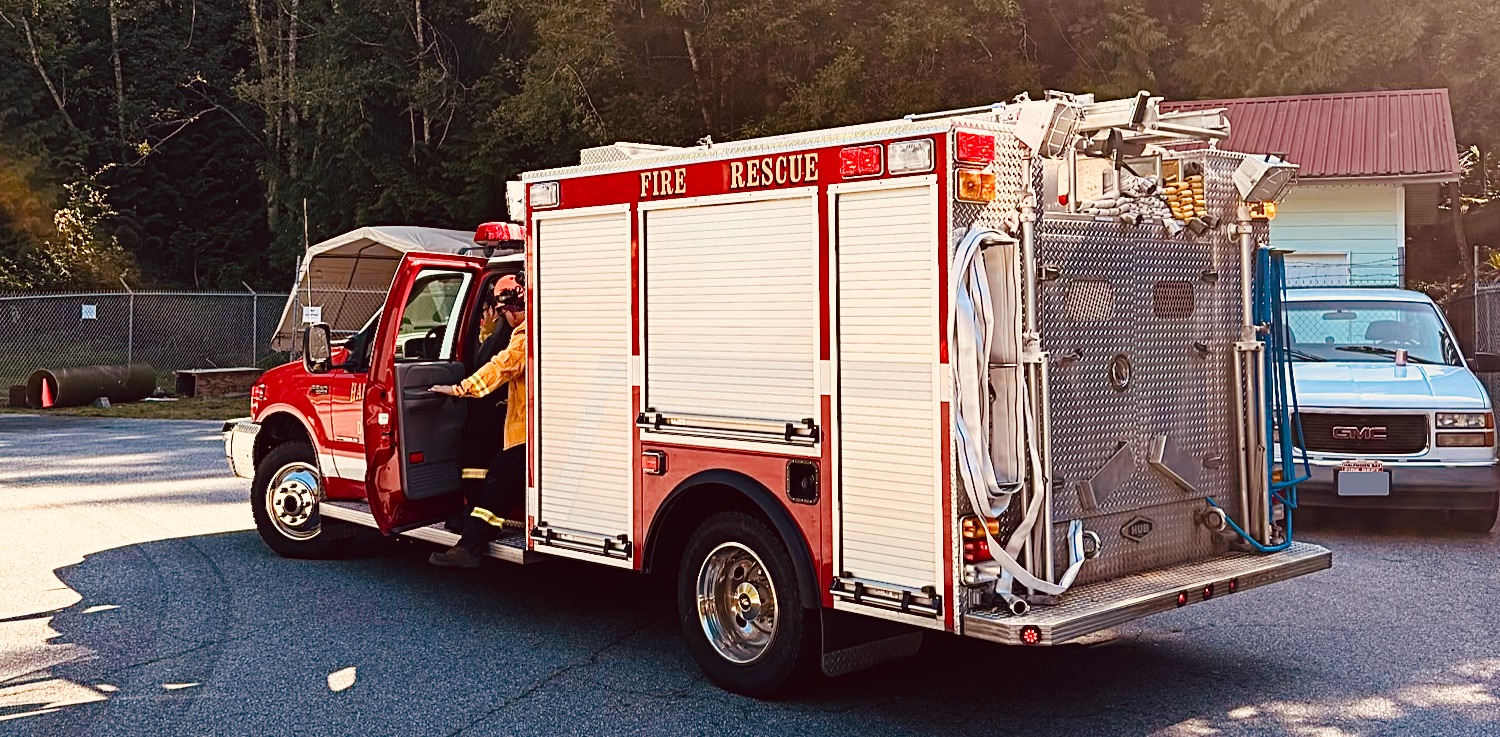 A small red fire engine with a wildland firefighter stepping out of it