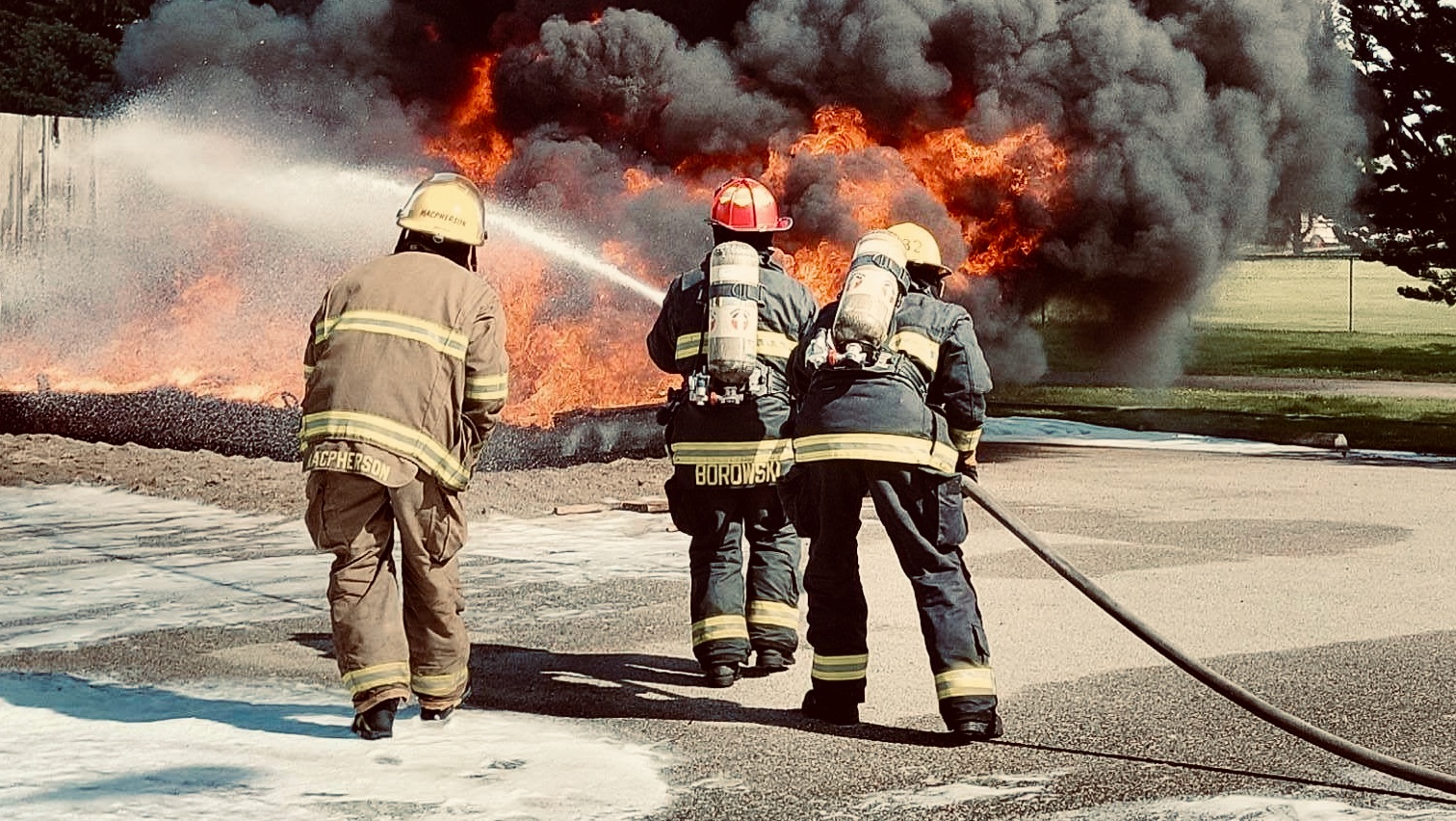 Two firefighters putting water on a flammable liquid fire